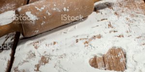 Kitchen rolling pin and with flour on wooden background.